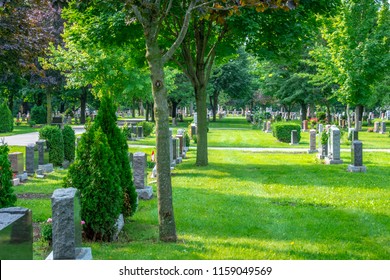 A beautiful graveyard marked with rows of headstones and lined with trees, flowers and walking paths, providing a peaceful setting for visitors to visit departed beloved friends and family members.