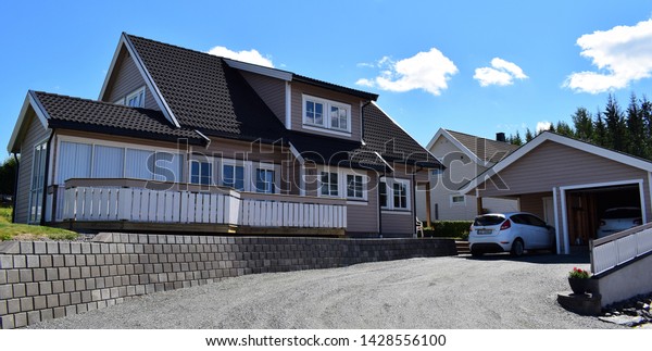 Beautiful gray house, black roof tiles, terrace and\
garage exterior and facade outdoor in sunny and summer season -\
wonderful blue sky estate and scenery - Norway Norwegian (16th june\
2019)