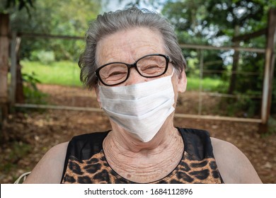 Beautiful Gray-haired Old Grandmother From The Yard Of The House In A Medical Mask With Glasses And Straightens The Mask And Looks. Covid-19. Coronavirus.