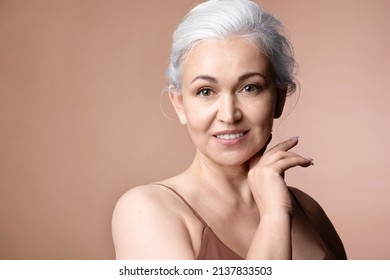 Beautiful  Gray-haired Senior Woman With Naked Shoulder And Perfect Groomed Skin, Studio Portrait On Blue With Copy Space. Attractive Mature Lady Touching Neck. Beauty And Aged Skincare Concept