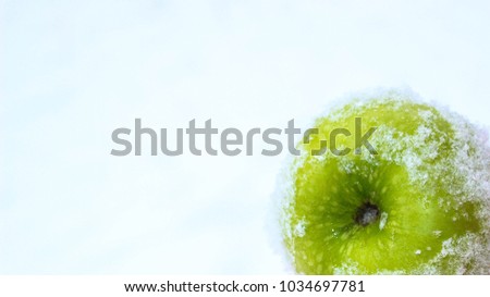 A beautiful green apple is scattered over white fluffy snow. Green apples on a white background. Close-up.