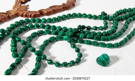 Beautiful green beads made of Russian malachite on a white plastered background. Natural energetic stone. Ancient Slavic culture. Vintage jewelry.