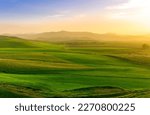 beautiful green valley with green fields with green spring grass with nive hills and mountains and scrnic colorful cloudy sunset on background of landscape