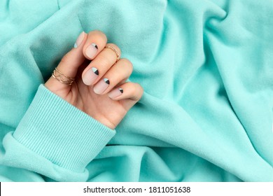 Beautiful groomed womans hand with nude and blue matte nail design. Manicure pedicure beauty salon concept.