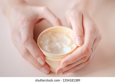 Beautiful groomed woman's hands with body and skin cream on a light background. Nourishing oil for clean and soft skin in winter time. Healthcare concept.