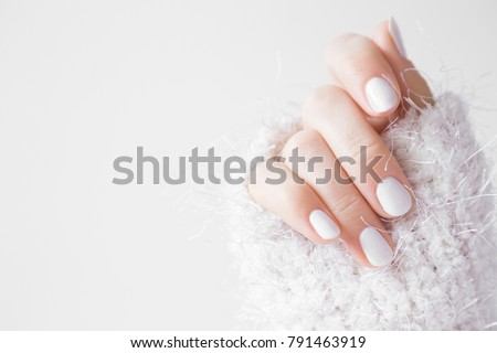 Beautiful groomed woman's hands with white nails on the light gray background. Nail varnishing in white color. Manicure, pedicure beauty salon concept. Empty place for text or logo. 
