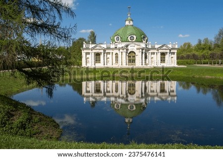 A beautiful grotto in Kuskovo park is reflected in the water of a pond on a sunny spring day.. Russia, Moscow.