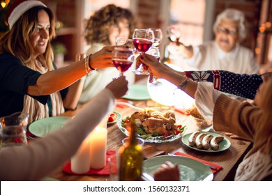 Beautiful group of women smiling happy and confident. Eating roasted turkey and toasting with cup of wine celebrating christmas at home - Powered by Shutterstock