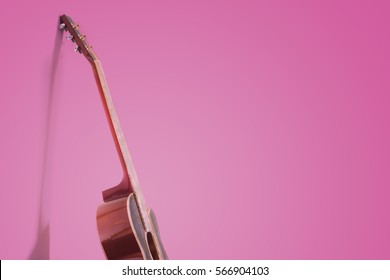 Beautiful guitar leaning on pink wall 