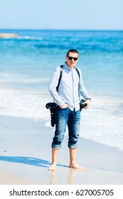 Beautiful  guy with a camera on the beach