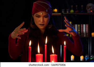 Beautiful Gypsy fortune teller woman doing cast a spell with hands around the candle. Fortune teller, Divine magic, Forecast esoteric astrology supernaturalism, magical power, alchemy concept. - Shutterstock ID 1669075006