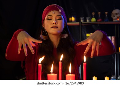 Beautiful Gypsy fortune teller woman doing cast a spell with hands around the candle. Fortune teller, Divine magic, Forecast esoteric astrology supernaturalism, magical power, alchemy concept. - Shutterstock ID 1672745983
