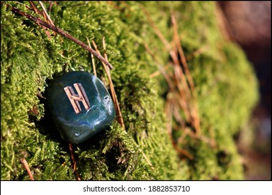 Beautiful Hagalaz Rune made of Bloodstone with mossy background