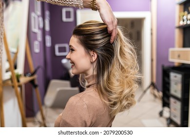 Beautiful hairstyle of young adult woman after dyeing hair and making highlights in hair salon.