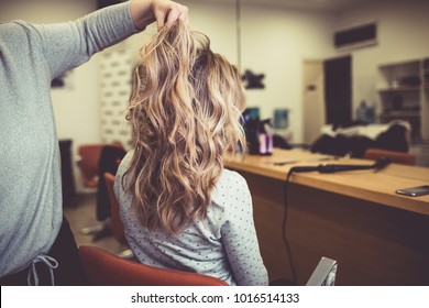 Beautiful hairstyle of young woman after dying hair and making highlights in hair salon. 