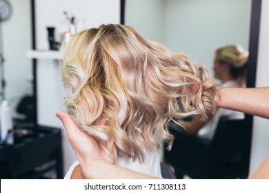 Beautiful hairstyle of young woman after dying hair and making highlights in hair salon.
