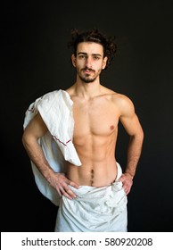 beautiful half naked bearded man with curly hair in a white drapery photo