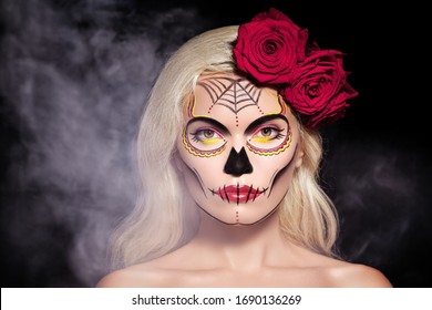 Beautiful Halloween Make-Up Style. Blond Model Wear Sugar Skull Makeup with Red Roses, pale Skin Tones and Waves Hair. Dia de los Muertos or Day of the Dead or Santa Muerte concept