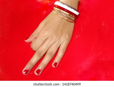 A Beautiful Hand, Finger With Cherry Or Red Colour Nail Polish, Bangles, A  Traditional White Conch Bangles, A Steel Bangle, Close Up With Red Background And Copy Space