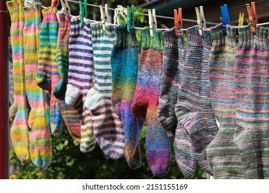 Beautiful Hand Knitted Socks Are Hanging On A Clothes Washing Line Outside To Dry Eco Friendly In The Wind And Sunshine.