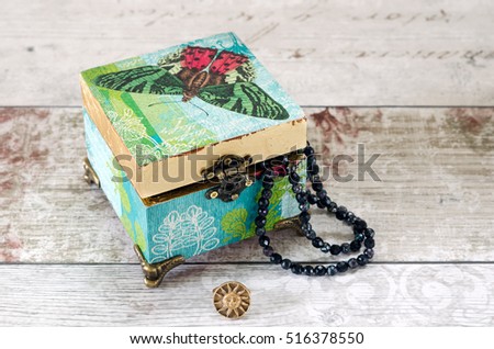 A beautiful hand made trinket box decoupaged in vintage papers and gilded with gold leaf, on a shabby chic background