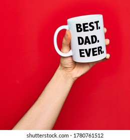 Beautiful hand of man holding cup of coffee with best dad ever message over isolated red background