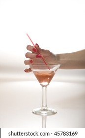 Beautiful hand with perfect red manicure holding martini glass .
