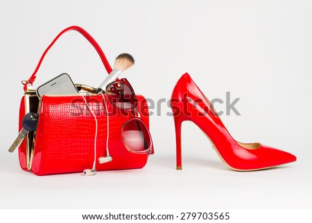Beautiful handbag with women's accessories stands near the red shoes.