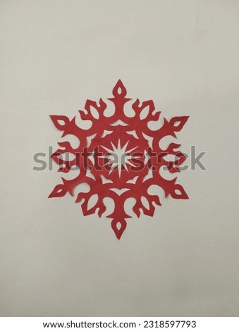 A beautiful handcrafted paper snowflake design in red colour on white background 