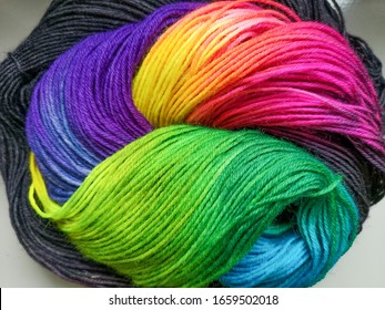Beautiful handdyed yarn with black and rainbow Colors is wound up in a Beautiful ball to present the yarn