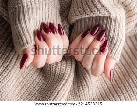 Beautiful hands of a young woman with dark red manicure on nails. Autumn winter nail design concept of beauty treatment.