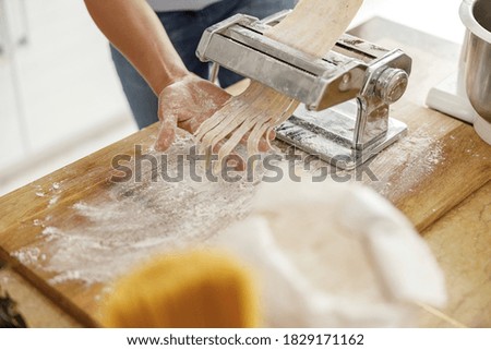 Beautiful handsome woman is preparing tasty fresh raw italian pasta at her kitchen at home