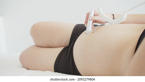 Beautiful Happiness Pregnant Woman Does Ultrasound Probe Moving Over Belly On Her Self, Using Fetal Doppler Device For Listening Baby Heartbeat Device, Motherhood Health Care Baby	
