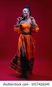 Beautiful Happy African Woman In Traditional Dress Dancing On Red Background, Studio Shot