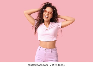 Beautiful happy African-American woman with sunglasses on pink background