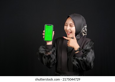 Beautiful Happy Asian Muslim Girl Pointing At Green Screen Phone On Black Background