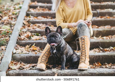 Beautiful And Happy Blond Woman Enjoying In Park Walking With Her Adorable French Bulldog. Selective Focus On Dog.