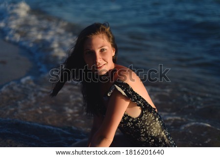 Beautiful happy carefree young woman sitting and relaxing on the beach.