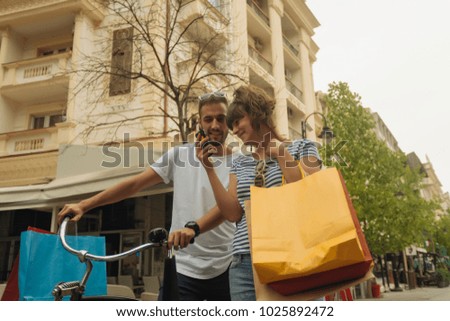 beautiful happy couple holding shopping bags and making selfie with cellphone in the city. shopping concept.