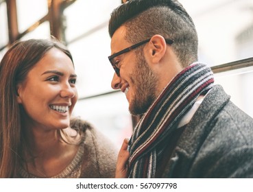 Beautiful Happy Couple Looking At Each Other's Eyes Traveling On A Old Vintage Tram Bus  - Stunning Woman Smiling To Her Boyfriend And Pulling His Scarf - Focus On Man Eye