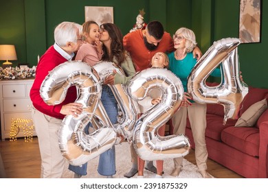 Beautiful happy family celebrating Christmas at home, having fun holding giant balloons shaped as numbers 2024, representing the upcoming New Year - Powered by Shutterstock