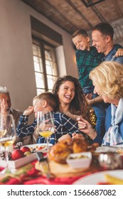 Beautiful Happy Family Gathered Around The Table, Having Christmas Dinner, Enjoying Their Time Together And The Winter Holiday Season