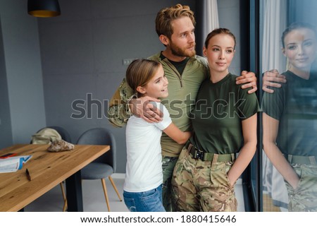 Beautiful happy family hugging while looking out window at home