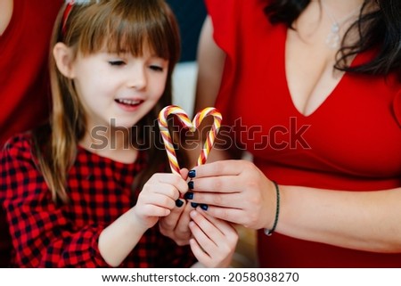 beautiful and happy family on the couch with lollipops. mom, dad and daughter in New Year's clothes. celebration of Christmas. family traditions. photo shoot.