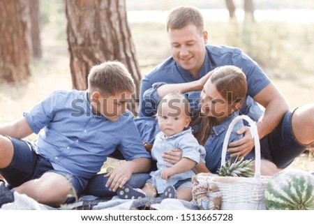 Beautiful happy family - parents and two sons, spend time in nature, laughing, eating fresh fruits