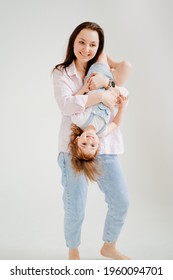 Beautiful Happy Family At A Photo Shoot In A White Photo Studio. Backstage. Mom And Daughter Play And Have Fun. Mother's Day