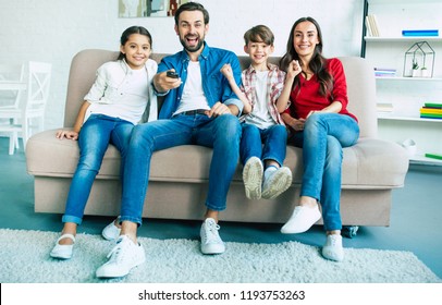 Beautiful Happy Family Watch TV On The Couch At Home And Smiling