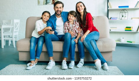 Beautiful happy family watch TV on the couch at home and smiling