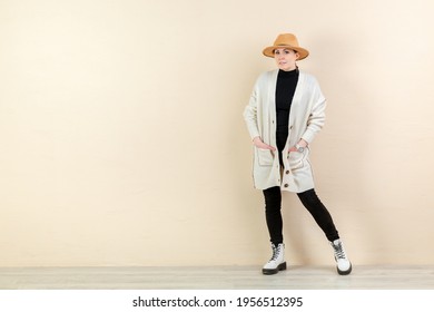 Beautiful Happy Girl In A Bright Cardigan And A Yellow Hat In Emotions Near The Yellow Wall. Place For Content