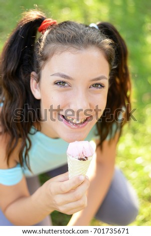 Beautiful happy girl eating ice cream outdoors at sunset. Teenage girl eats ice cream. Enjoyin ice cream